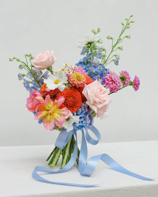 Colorful bouquet of flowers with a blue ribbon on a light gray background