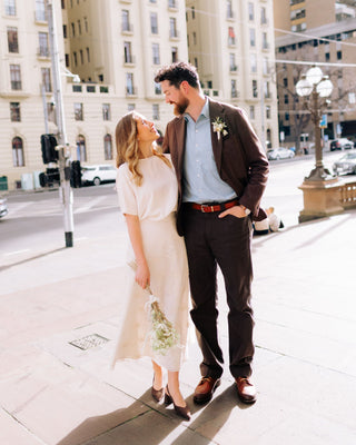 Couple standing on a city street, smiling at each other.