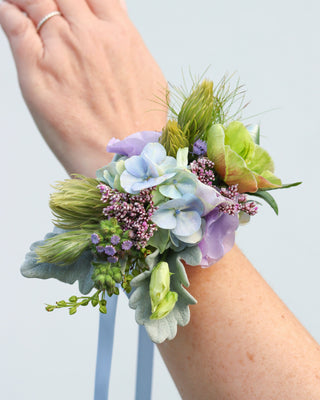 Floral wrist corsage on a person's wrist against a light background